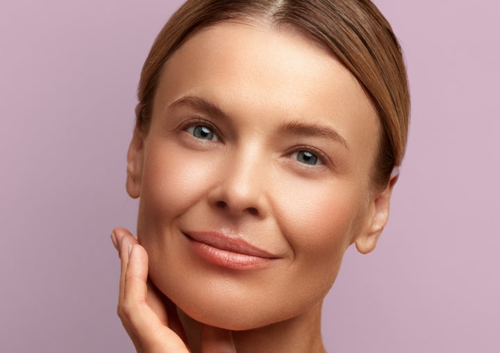 A woman is touching her face with her hand and smiling