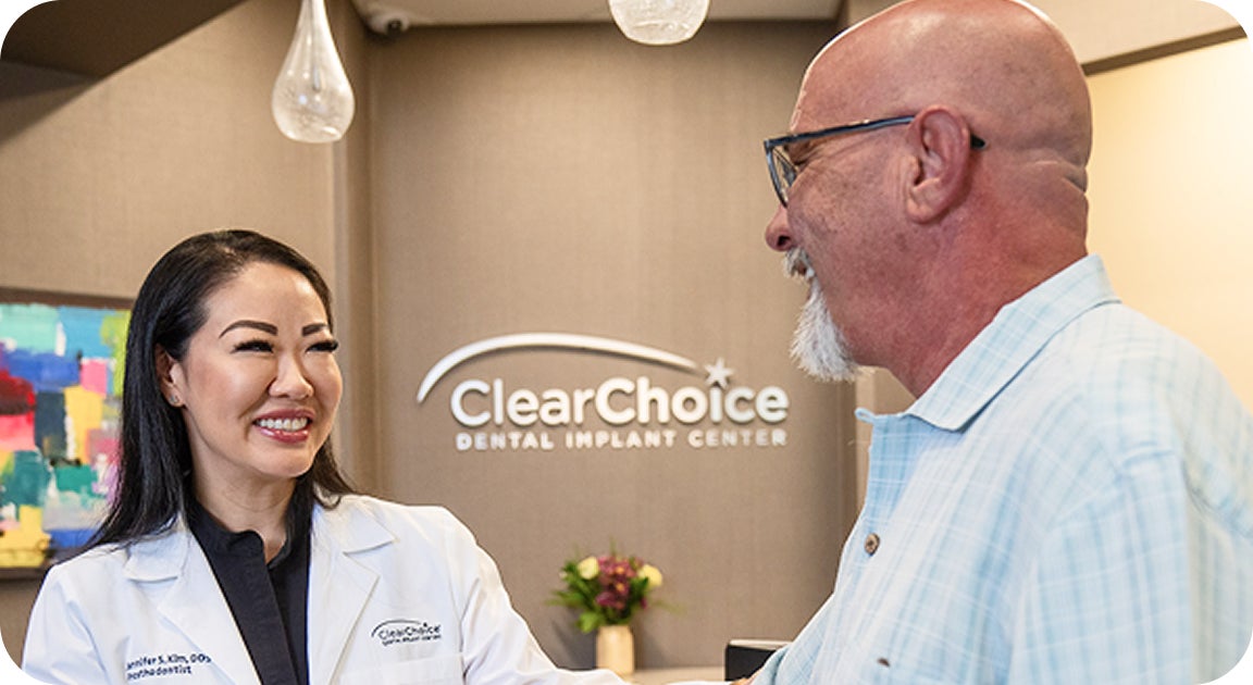 A ClearChoice doctor warmly greets a senior patient in the center lobby, illustrating the supportive start of a treatment journey for those transitioning from years of dentures to dental implants.