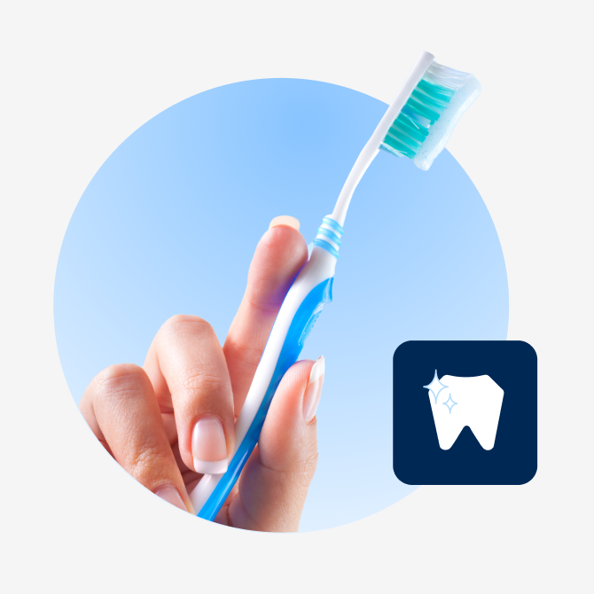 Hand holding a blue toothbrush with green bristles against a light blue background, with an icon of a tooth next to it.