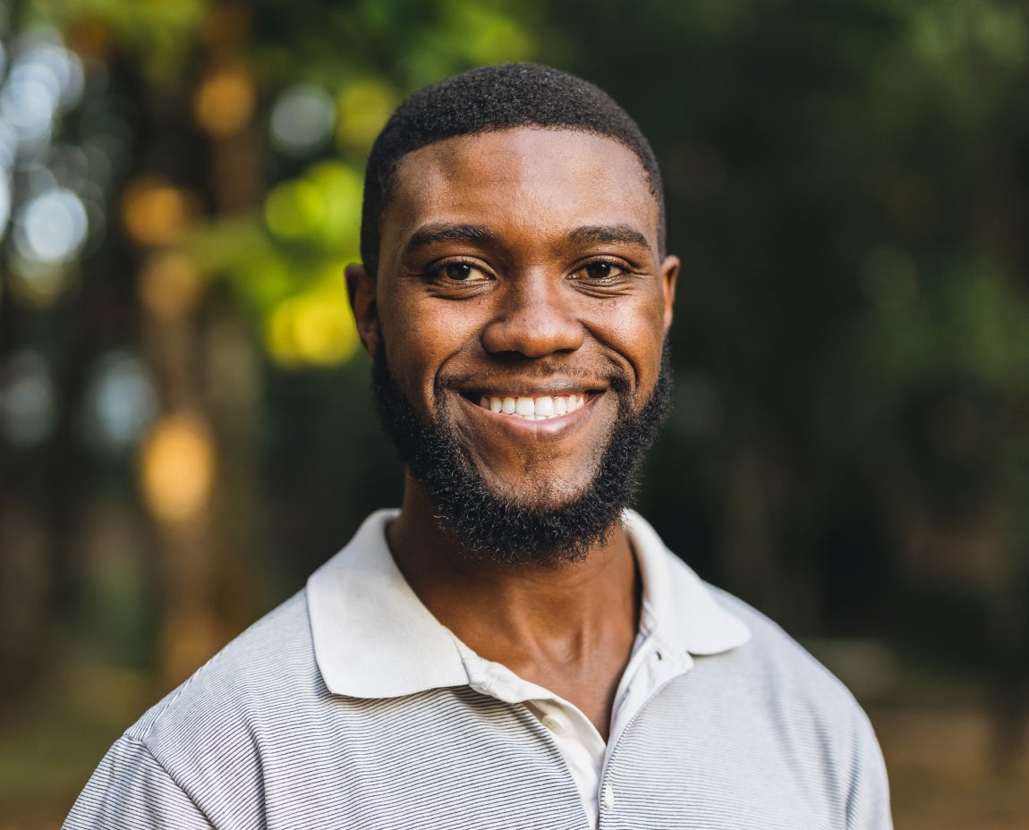A smiling man outdoors showcasing his confident smile after successful dental implant surgery at Aspen Dental.