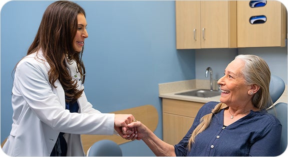 A ClearChoice prosthodontist shaking hands with her patient, who has fully recovered from her dental implant and restored her eating function.