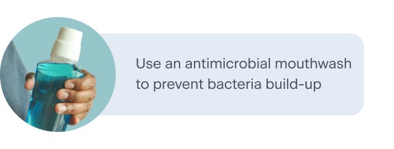 A hand holding a bottle of blue antimicrobial mouthwash with a white cap. The text advises using an antimicrobial mouthwash to prevent bacteria build-up, promoting better oral health.