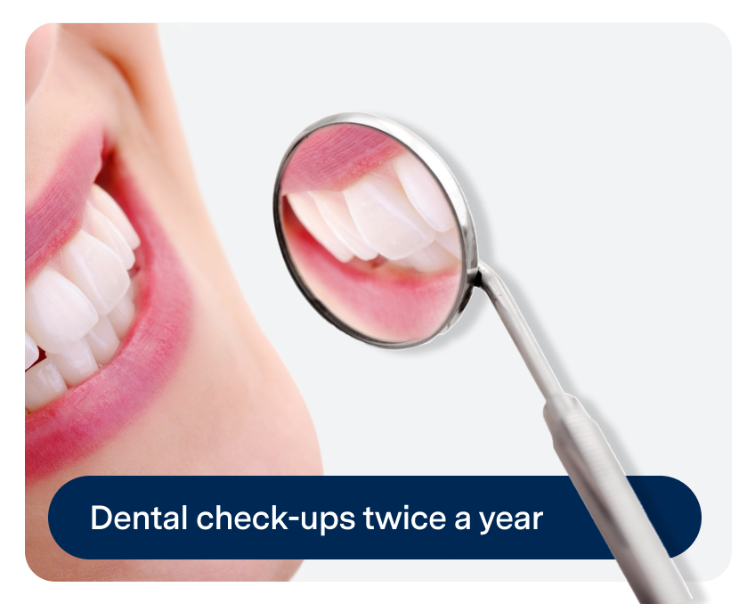 Close-up of a smiling mouth reflecting in a dental mirror. Text at the bottom says, "Dental check-ups twice a year.