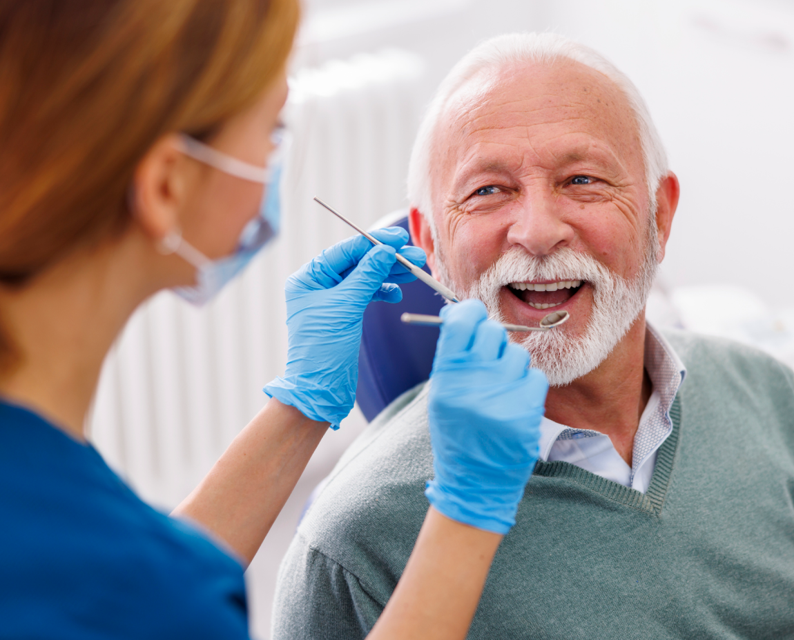 A dentist checking an older patient's removable dentures with implants during an annual dental checkup.