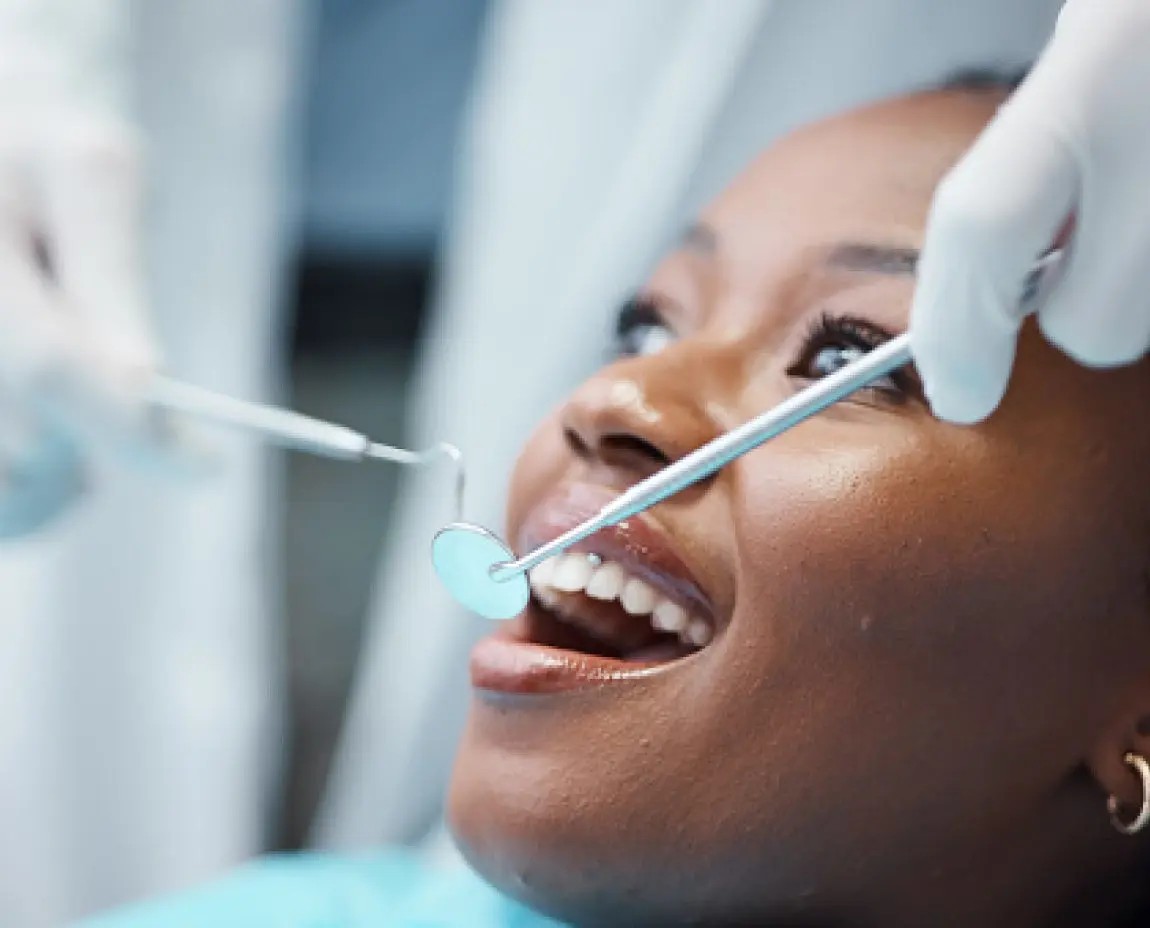 Close-up of a patient at Aspen Dental receiving a dental cleaning and oral exam with dental tools in a professional clinic setting.