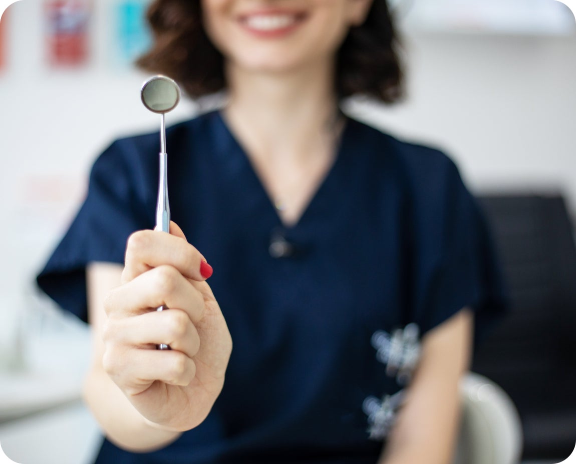 Aspen Dental provider holds a dental mirror and explorer, preparing to examine a patient’s amalgam fillings for signs of wear or decay.