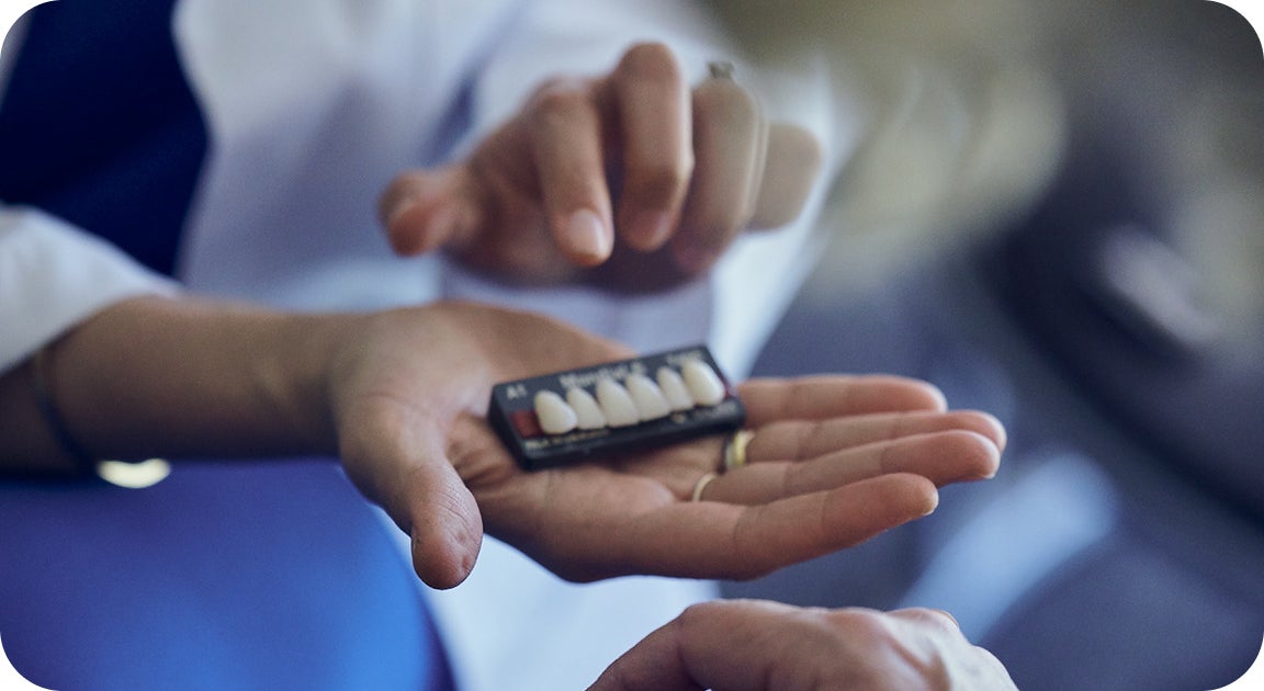 A ClearChoice doctor helping a patient find the most natural teeth shade suitable for them to create a customized smile, a procedure that lower cost dental implants may not include.