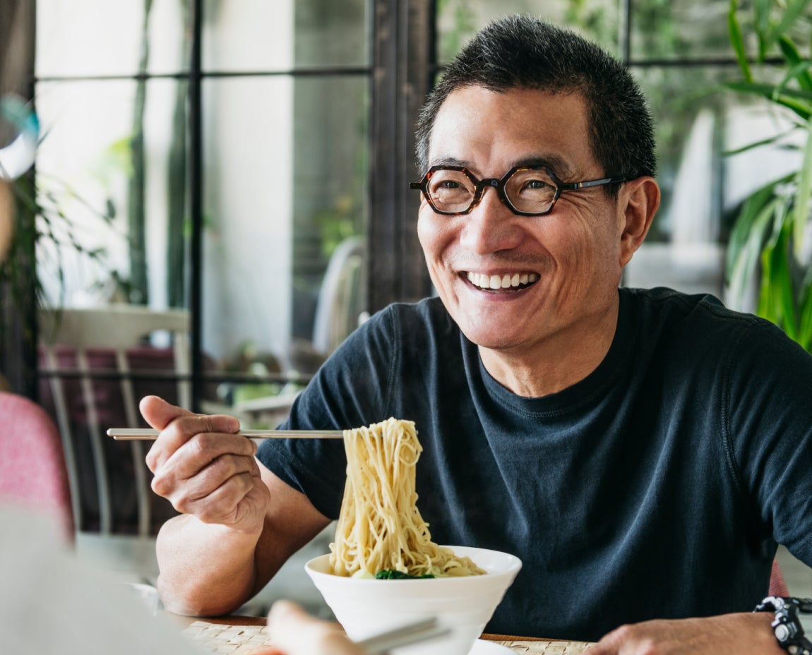  A person with short hair and glasses is smiling while holding chopsticks and eating noodles from a bowl.
Reply
