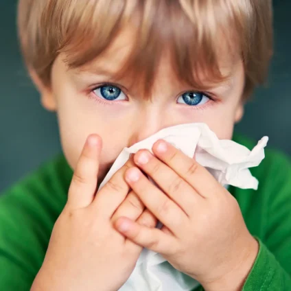 A child blows their nose into a tissue. 