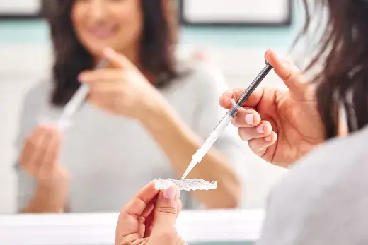 Motto Clear Aligners patient injecting whitening material into her clear aligner.