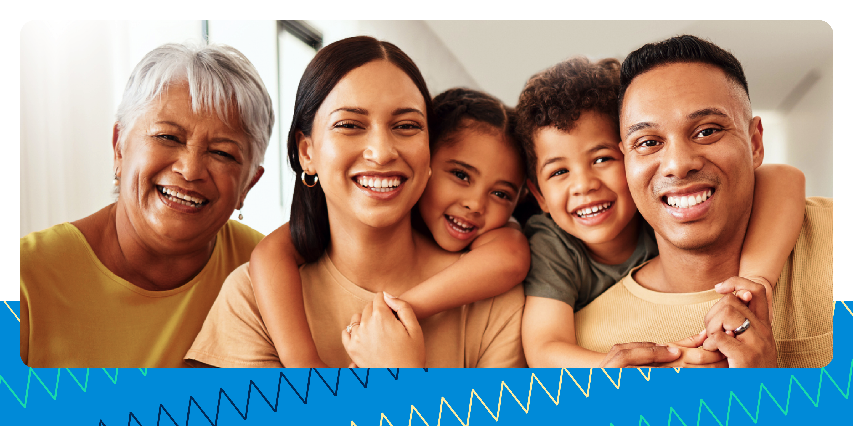 Una familia con una abuela, una madre, un padre y dos hijos (una niña y un niño) que están sonriendo y abrazándose.