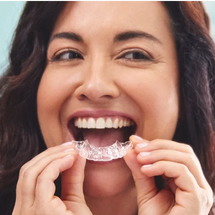 An Motto patient places Clear Aligners on their teeth.