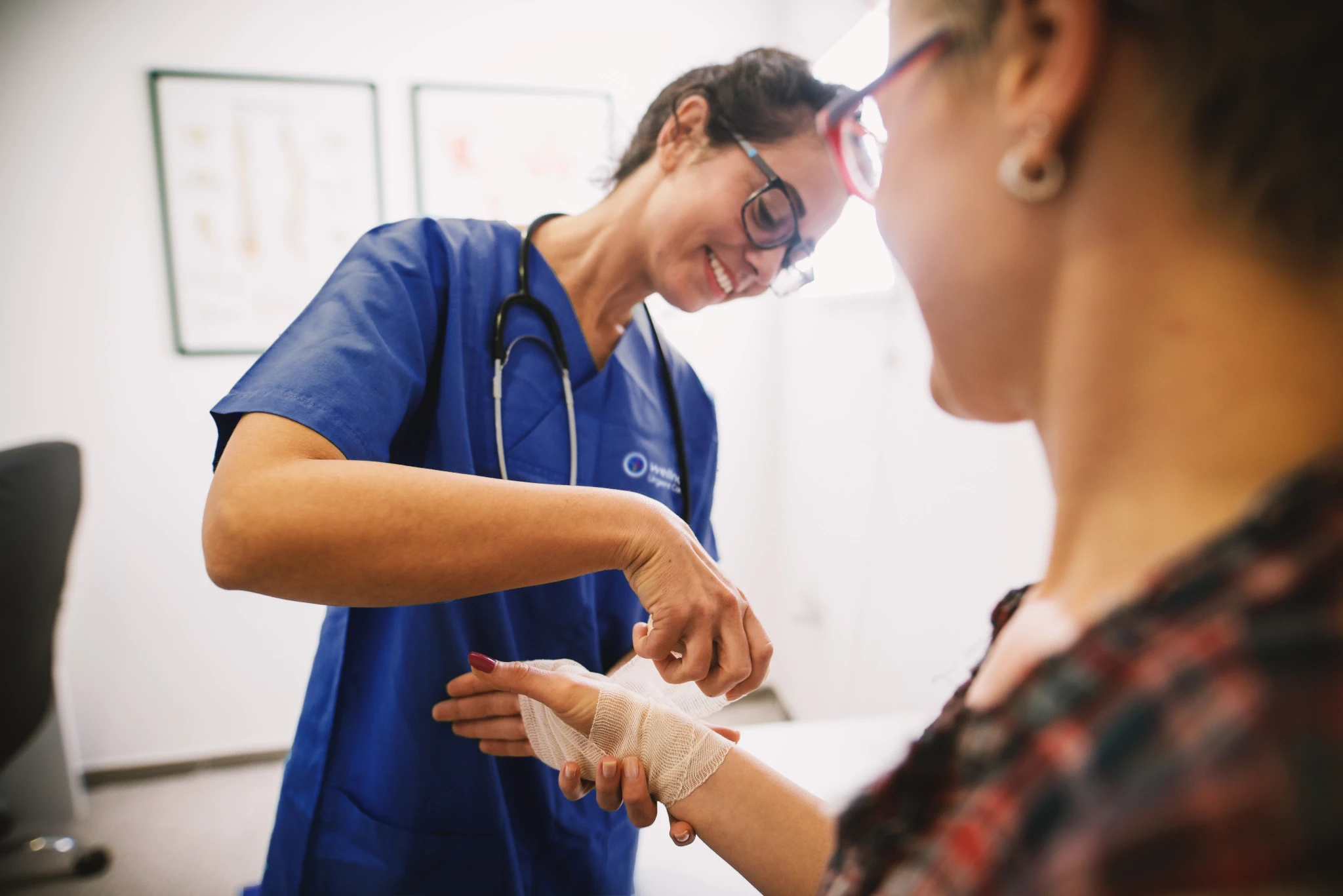 A WellNow Doctor wraps a patient's wrist in a bandage. 