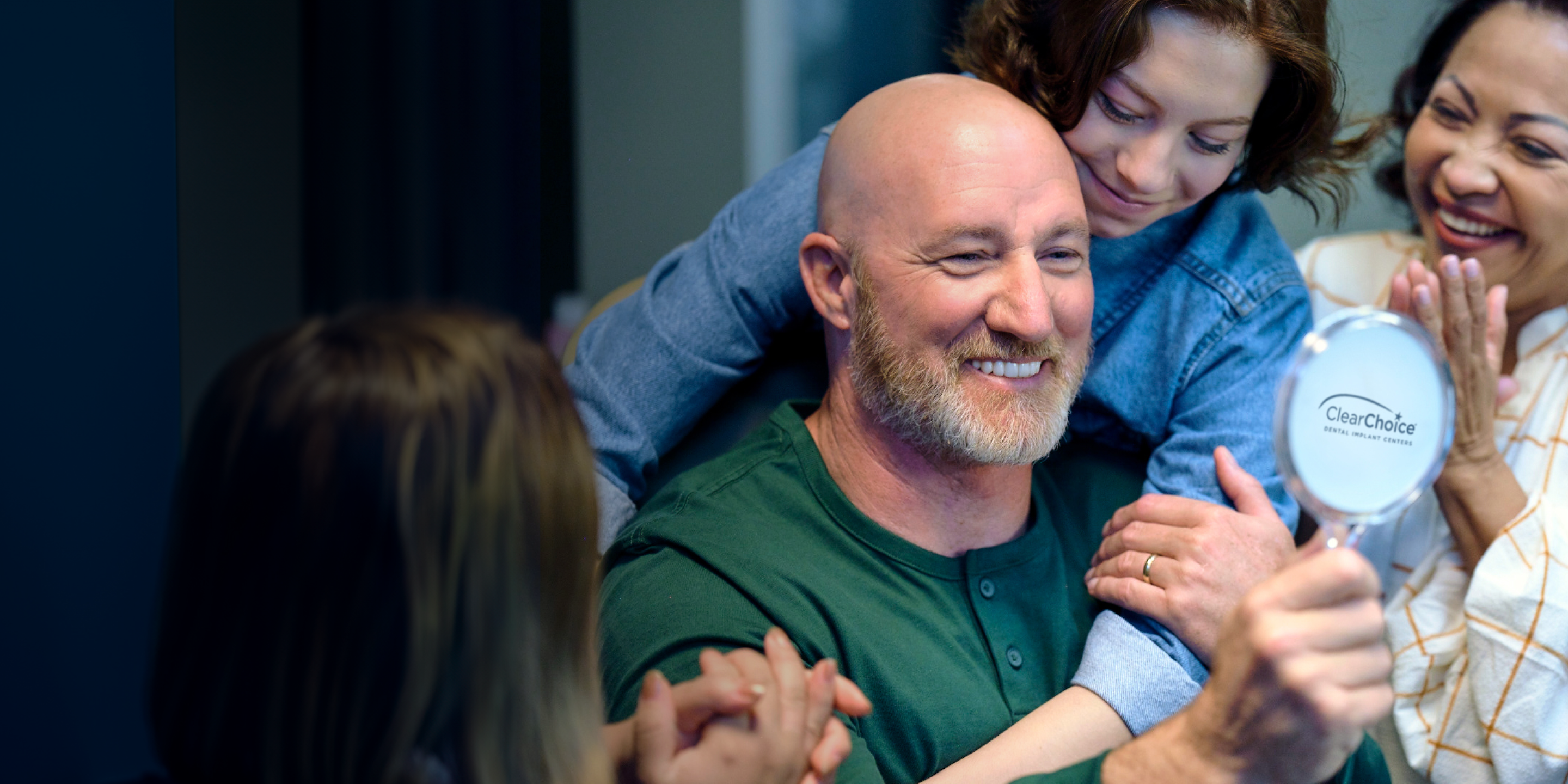 A man is smiling while looking at his dental implants in a ClearChoice mirror.