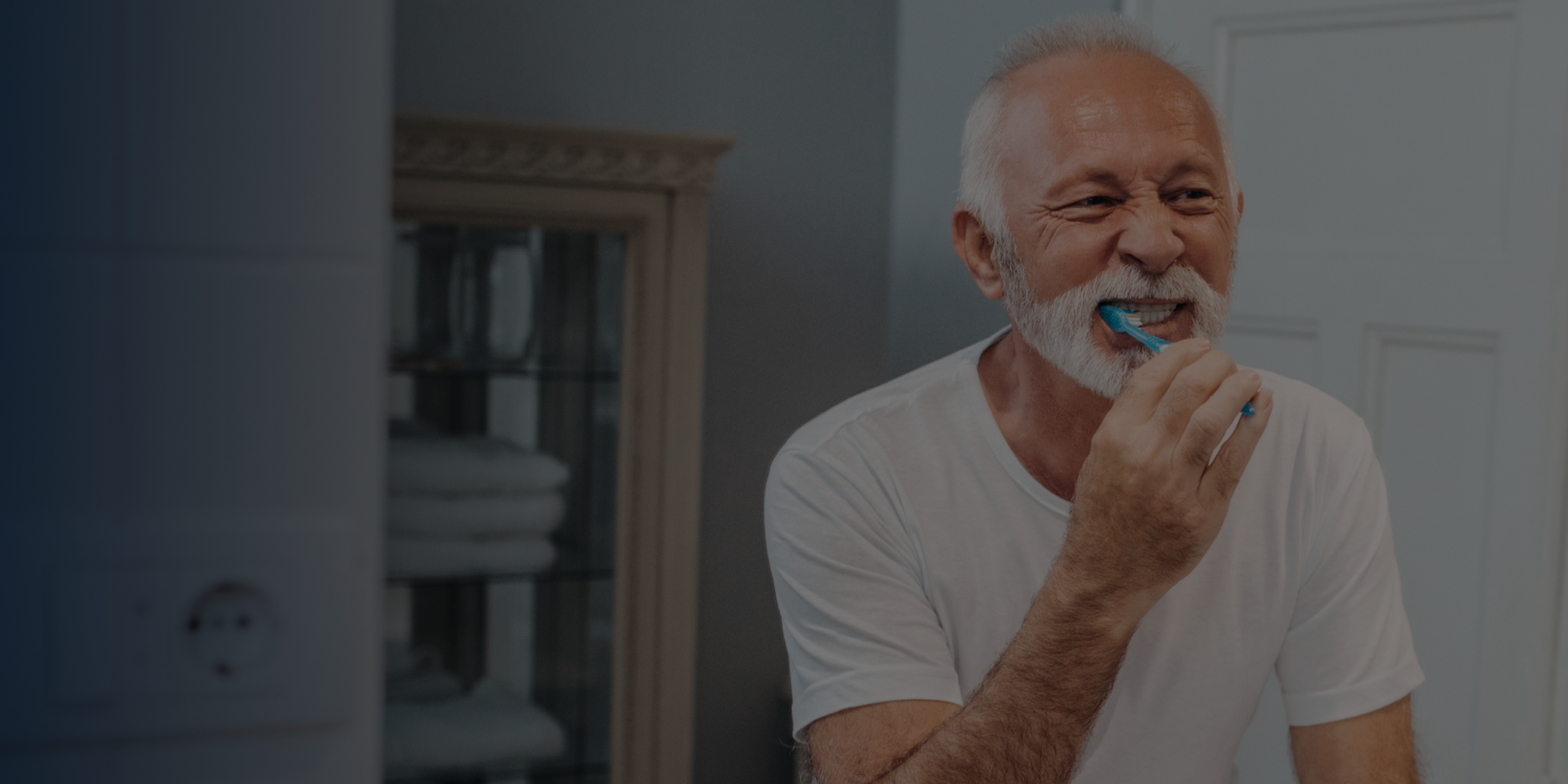 An Aspen Dental implants patient brushes their teeth in a mirror. 