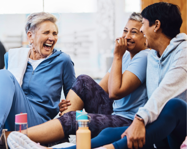 Group of senior women laughing and enjoying a break during a workout session.