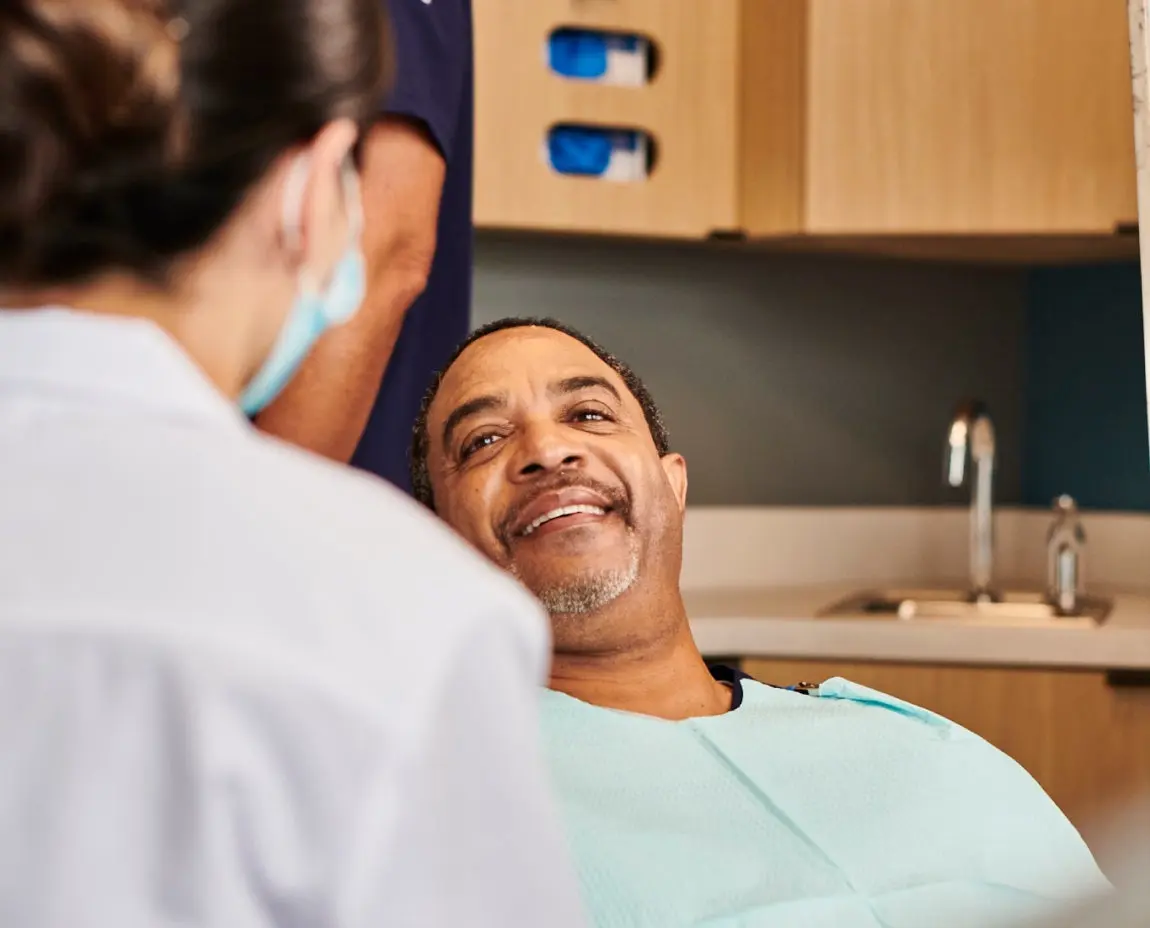 Patient smiling during a consultation with an Aspen Dental professional in a welcoming and modern clinic environment.