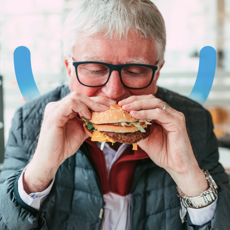 An Aspen Dental implants patient bites into a burger. 