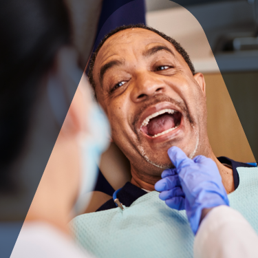 Aspen Dental dentist performing a dental checkup on a patient's teeth, ensuring his oral hygiene and maintaining his dental health.