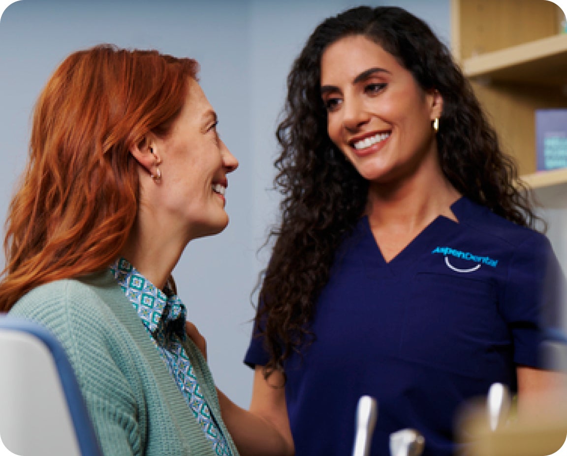 Smiling woman talks with a dental staff member after a root canal appointment. Suggests comfort and relief post-treatment.