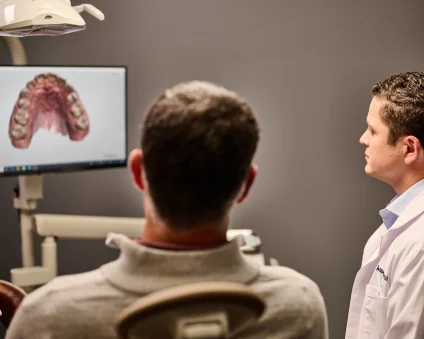 An Aspen Dental doctor presents a patient with a scan of teeth. 