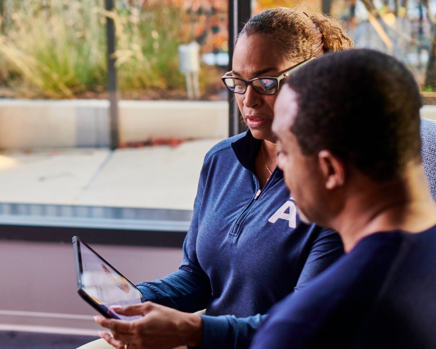 Aspen Dental team member reviewing treatment options on a tablet with a patient in a bright, modern office, emphasizing personalized care and technology.