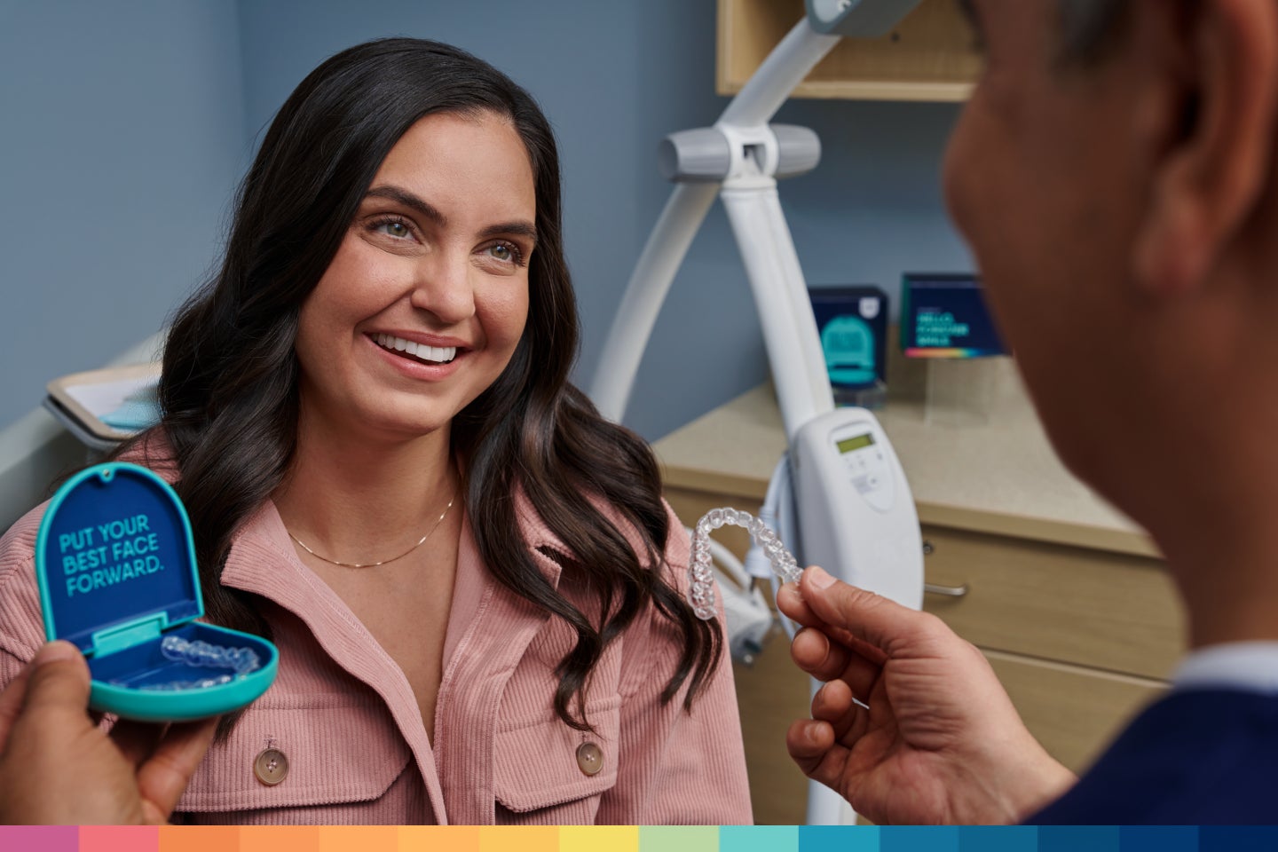 An Aspen Dental dentist presents Motto Clear Aligners to a smiling female patient