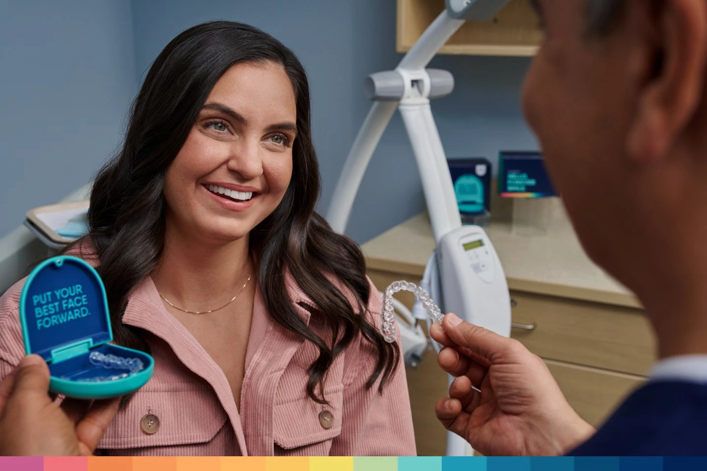 An Aspen Dental dentist presents Motto Clear Aligners to a smiling female patient