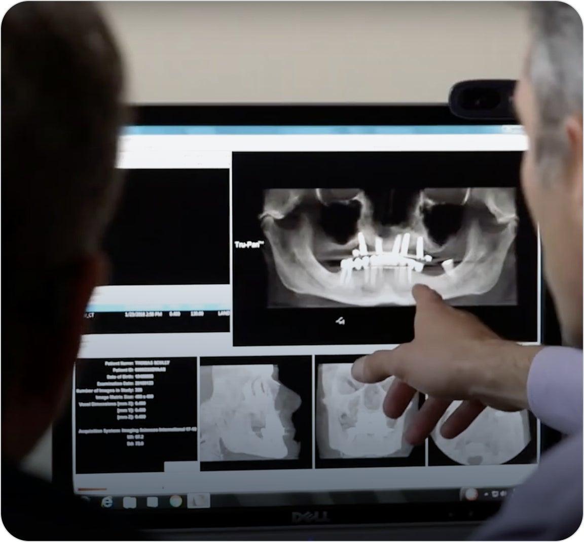 A ClearChoice oral surgeon walking his patient through the results of their scan and the subsequent surgical operations for their dental implant treatment.