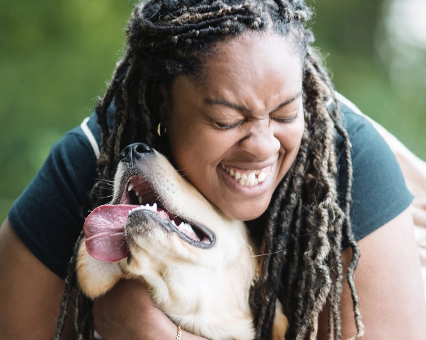 A smiling Lovet vet holds a flat-faced black and white cat.
