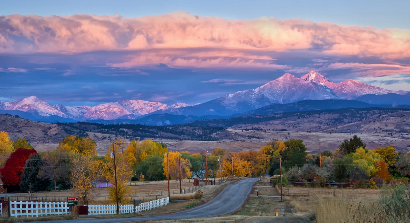 A view of a road leading up to mountains in Colorado at sunset