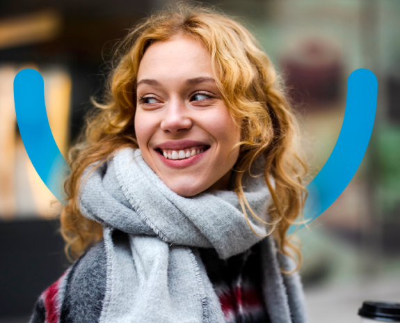 Smiling woman bundled in a scarf, representing confidence and satisfaction after dental care at Aspen Dental.