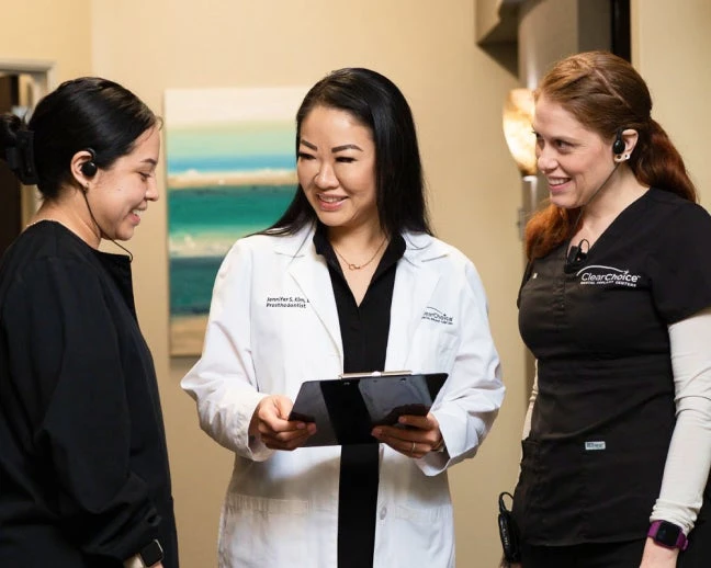 A woman in a lab coat is talking to two other women.