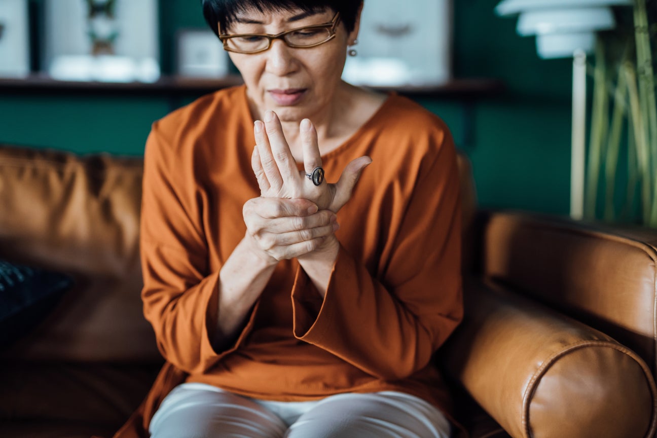 A woman sitting in a chair, holding her wrist in discomfort.