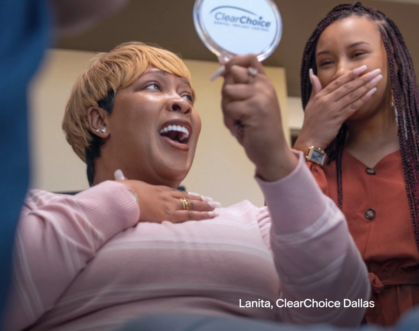 A woman is laughing while looking at her teeth in a mirror