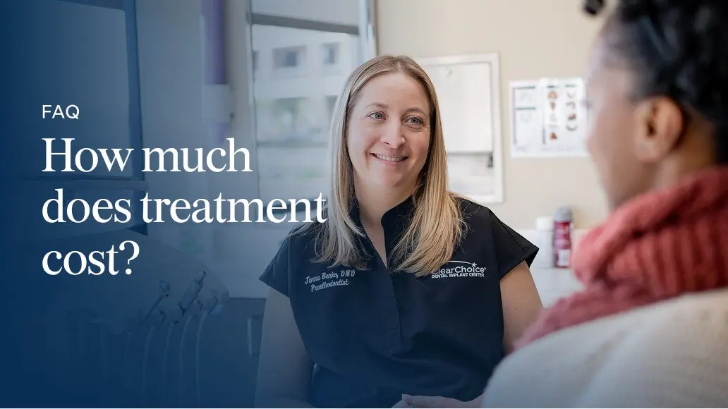 A ClearChoice dental specialist smiling while discussing treatment costs with a patient during a consultation in a modern clinic setting.