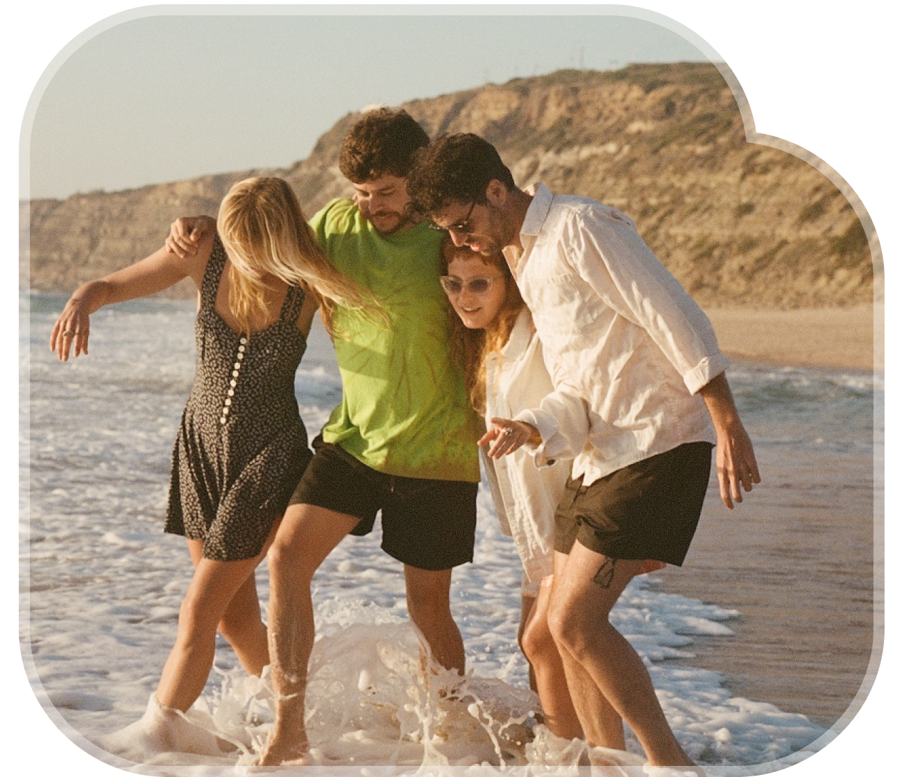 Four friends laughing together in the ocean waves at the beach