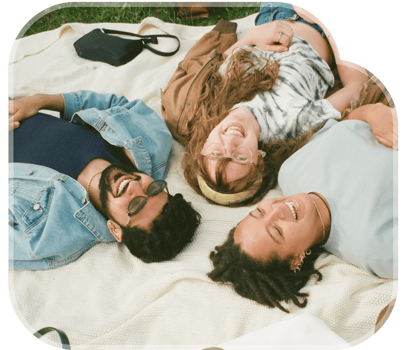 Friends lying on a blanket in a circle, smiling and looking up
