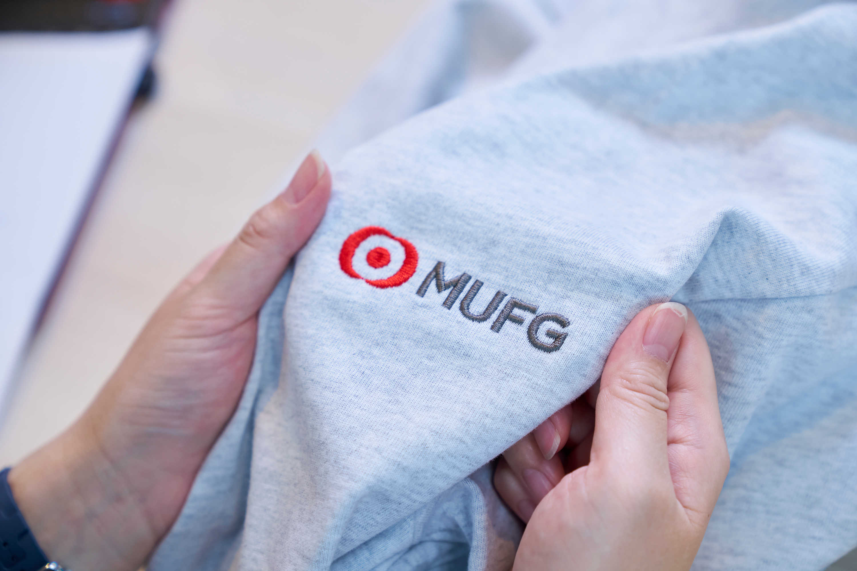 カーディガンにあしらわれたMUFGのロゴは、中心の円の位置がレギュレーションに抵触しないよう、何度もサンプル調整を重ねて仕上げられた