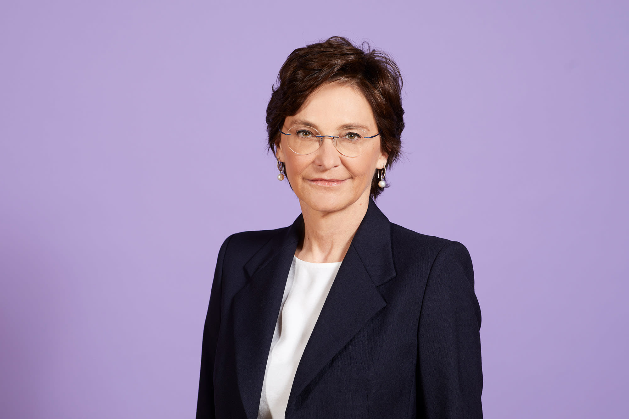 Bild von Claudia Höller in schwarzem Blazer vor lila Hintergrund. Bild von Claudia Höller in schwarzem Blazer vor lila Hintergrund.