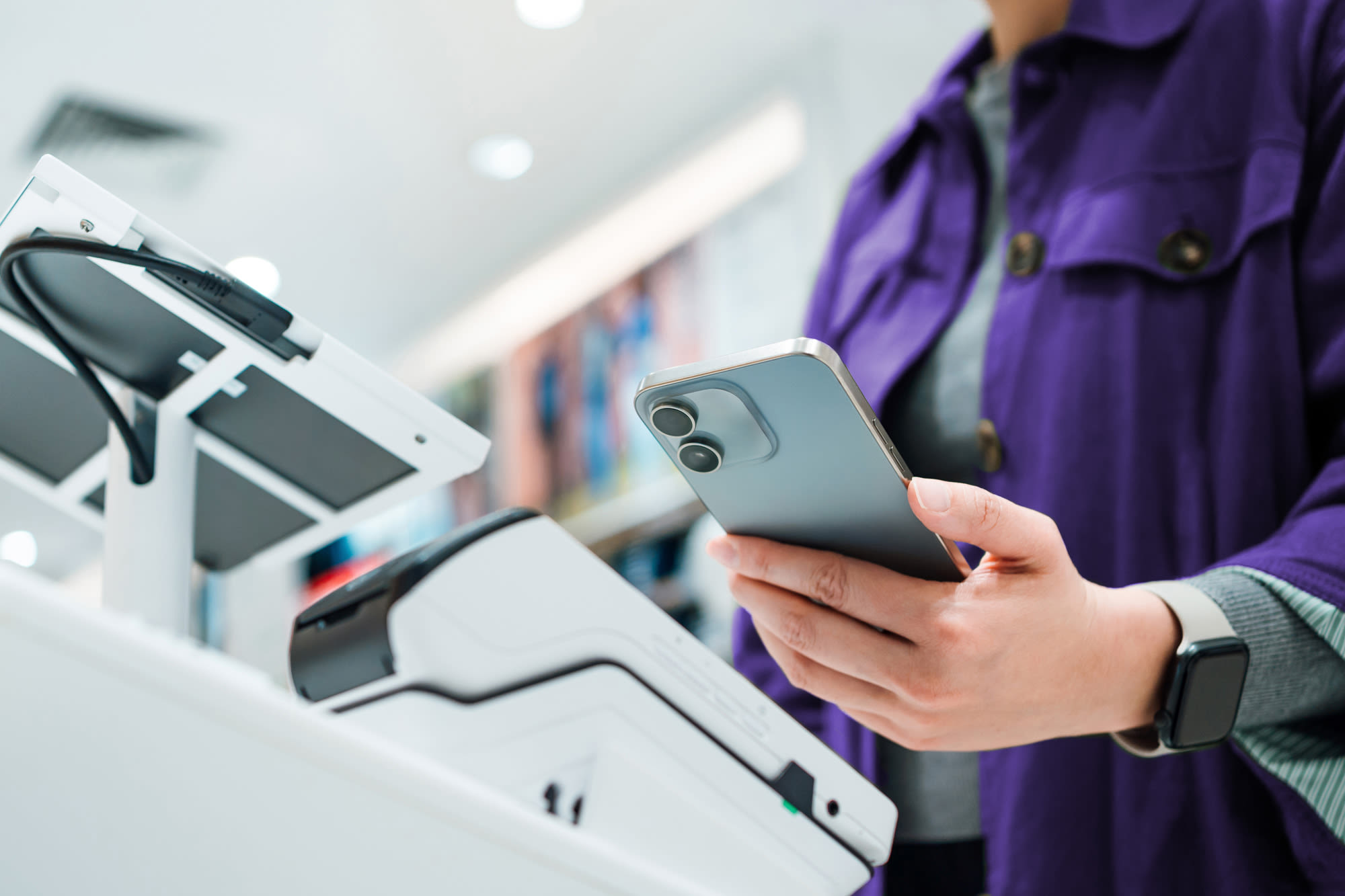 Kundin bezahlt kontaktlos mit dem Smartphone.