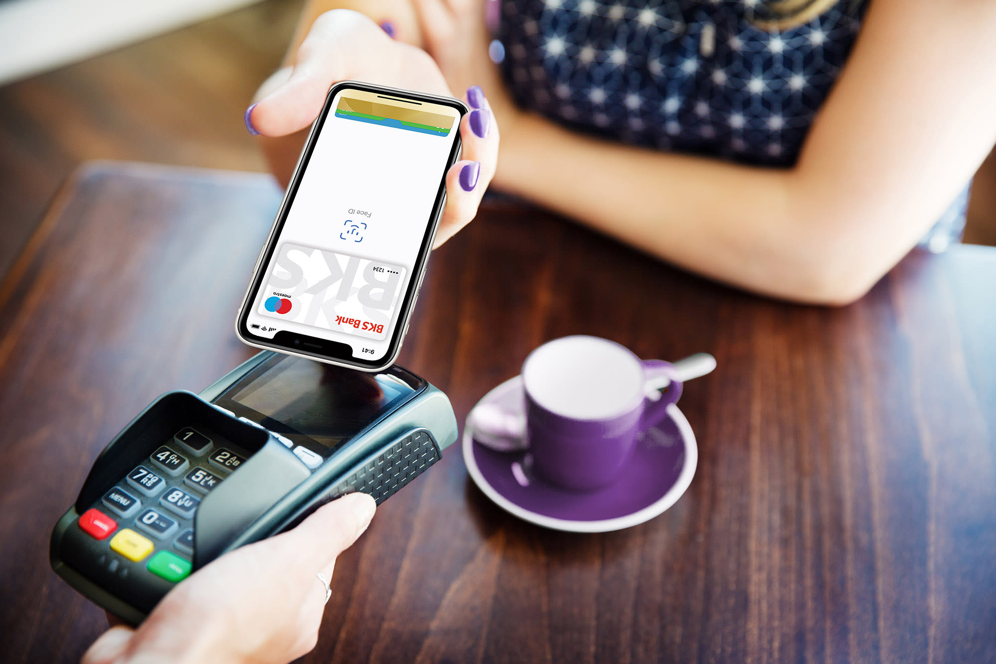 Frau zahlt mit Smartphone an Kartenlesegerät - Apple Pay bei der BKS Bank Frau zahlt mit Smartphone an Kartenlesegerät - Apple Pay bei der BKS Bank