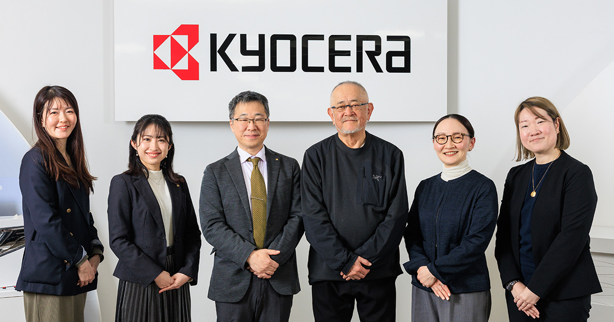 集合写真：京セラ様オフィスにて壁面コーポレートサインの前で。左から松田氏、篠原氏、北垣氏、橘、新山、三木が並ぶ。