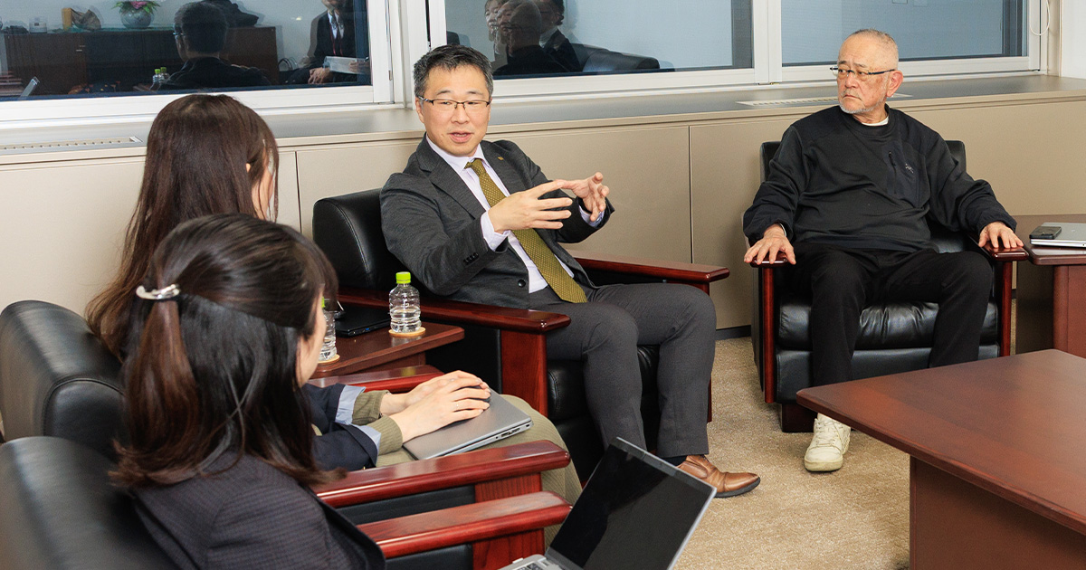 写真：右から橘、北垣氏、松田氏、篠原氏が椅子に座っている。北垣氏の話を皆が聞いている様子
