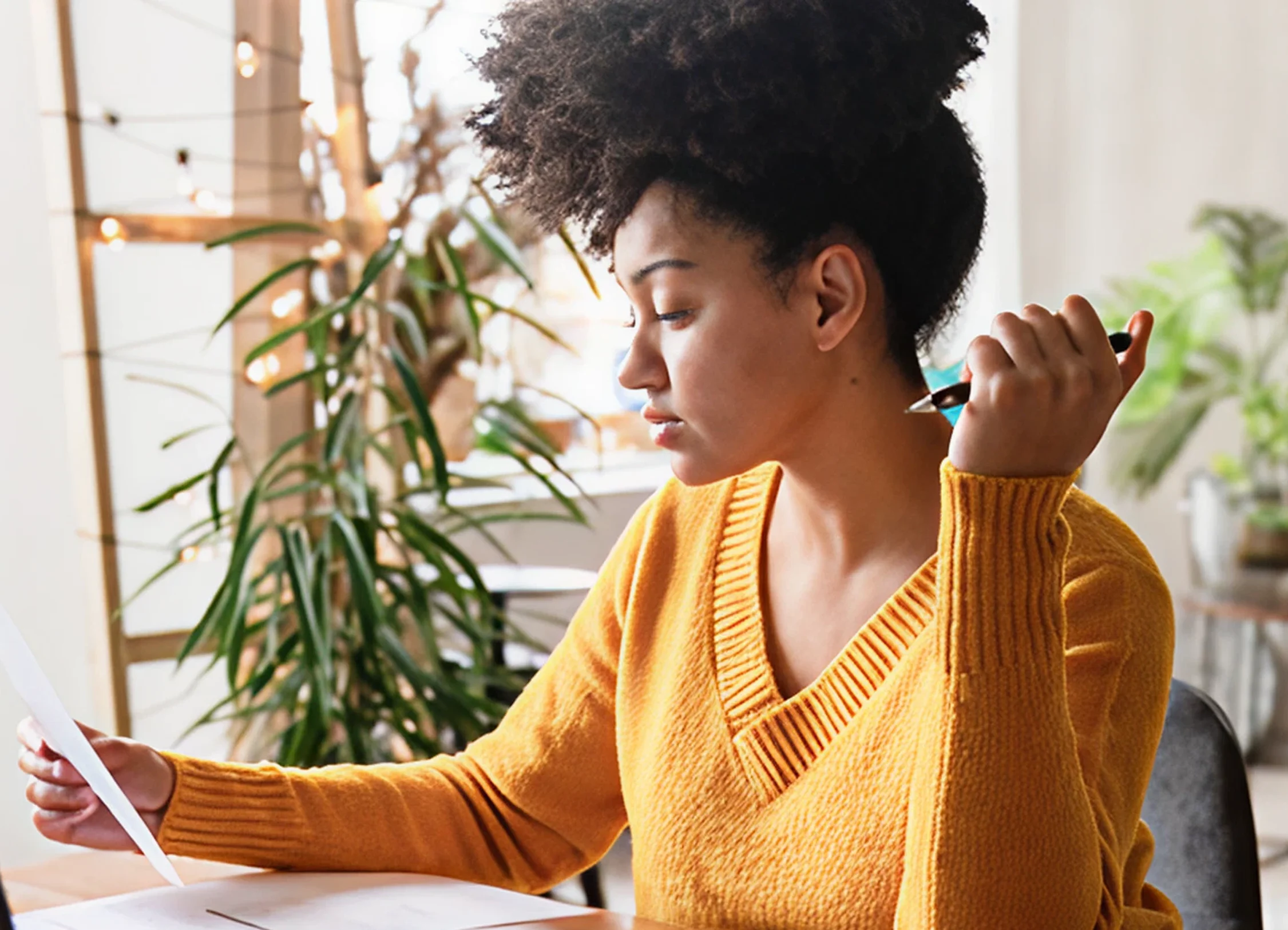 Woman holding a pen and looking at documents in front of her