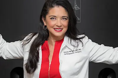 Dr. Vonda Wright posing in lab coat over a red dress. 