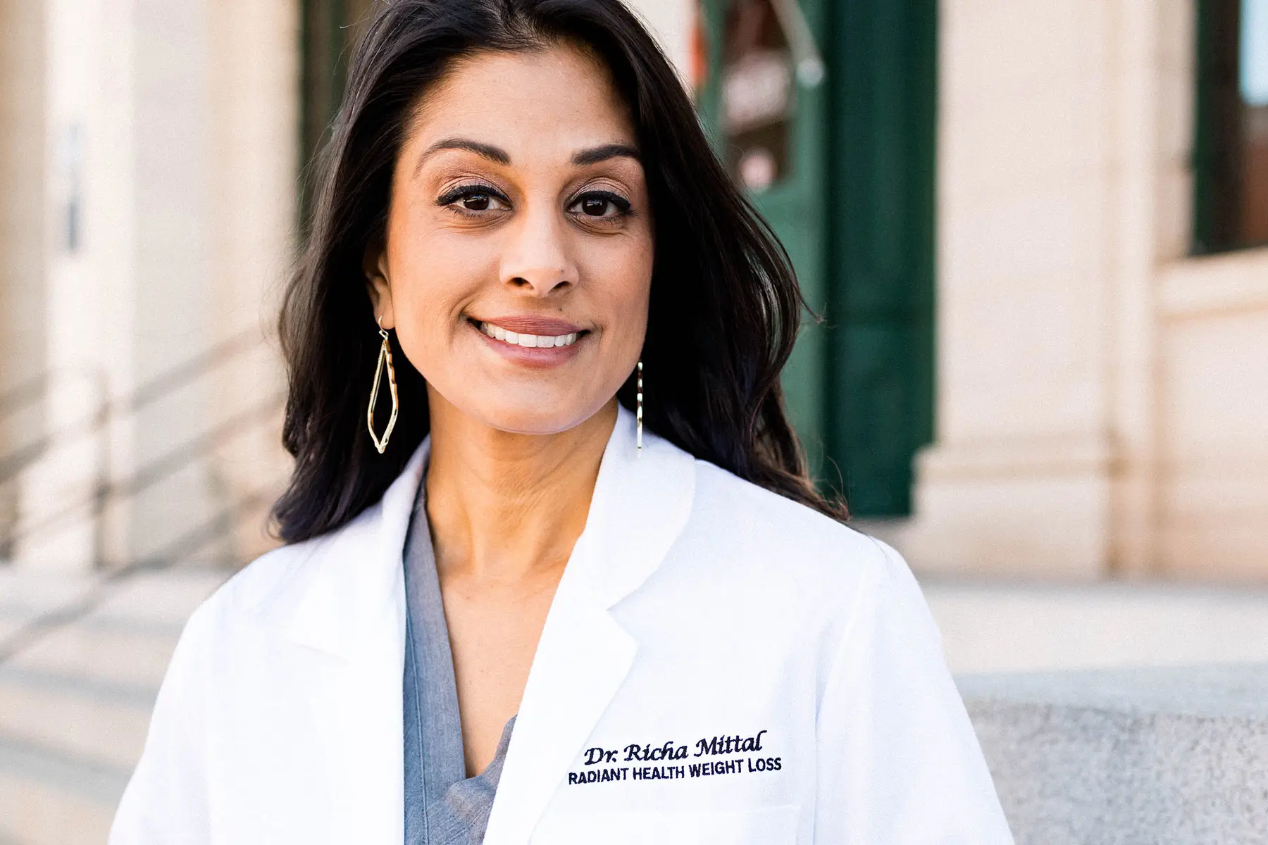 Dr. Richa Mittal in Lab Coat, smiling outdoors.