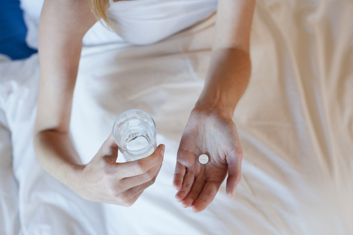 AW211 Paroxetine (photo of a woman sitting in bed with a glass of water preparing to take pill)