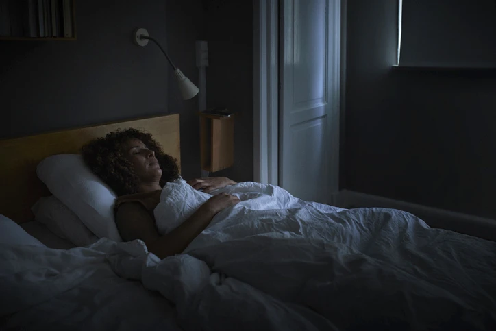 Bi-racial woman sleeping in a dim bedroom with blackout shades. AW266