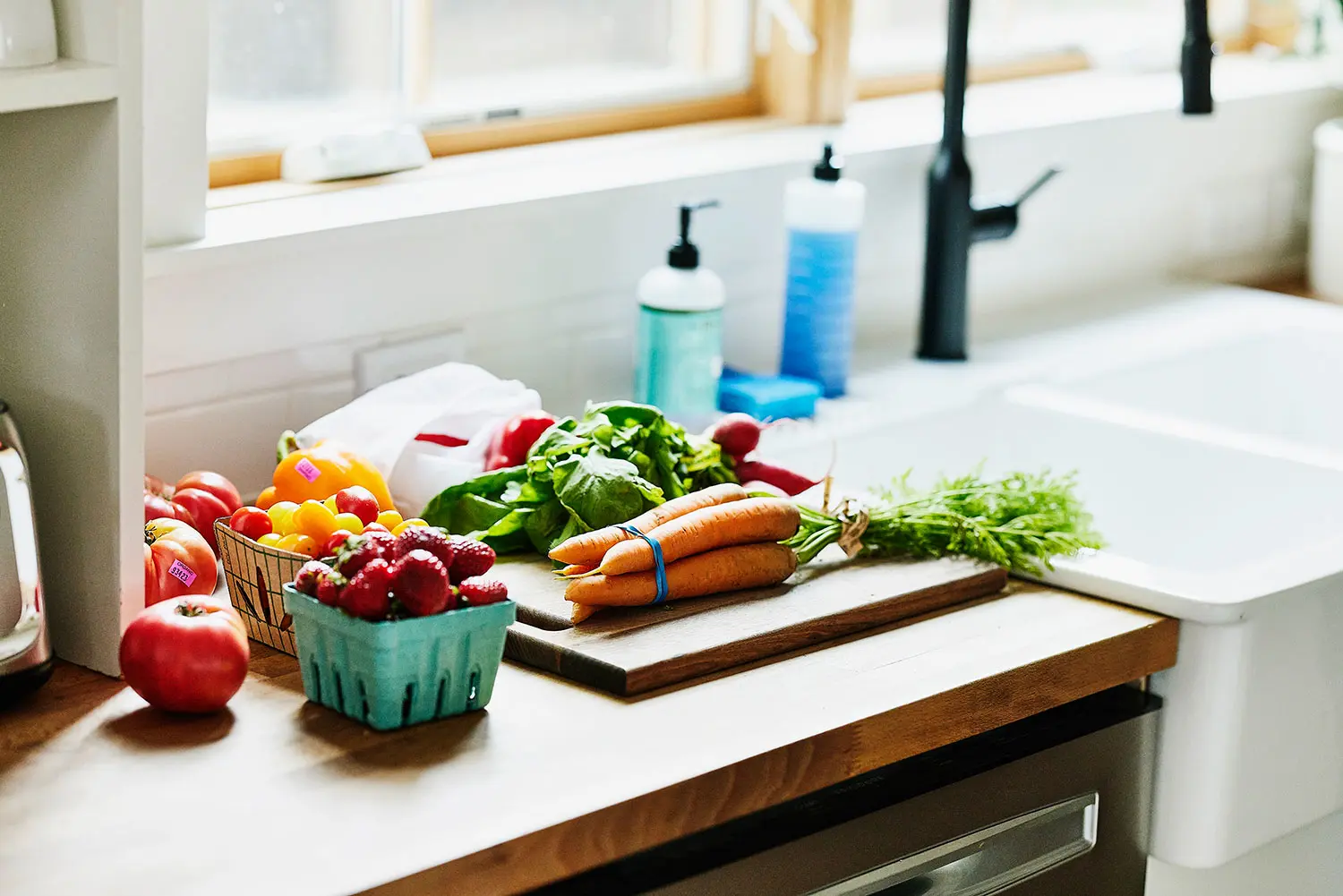 Fresh fruits and vegetables on cutting board next to sink. AW519